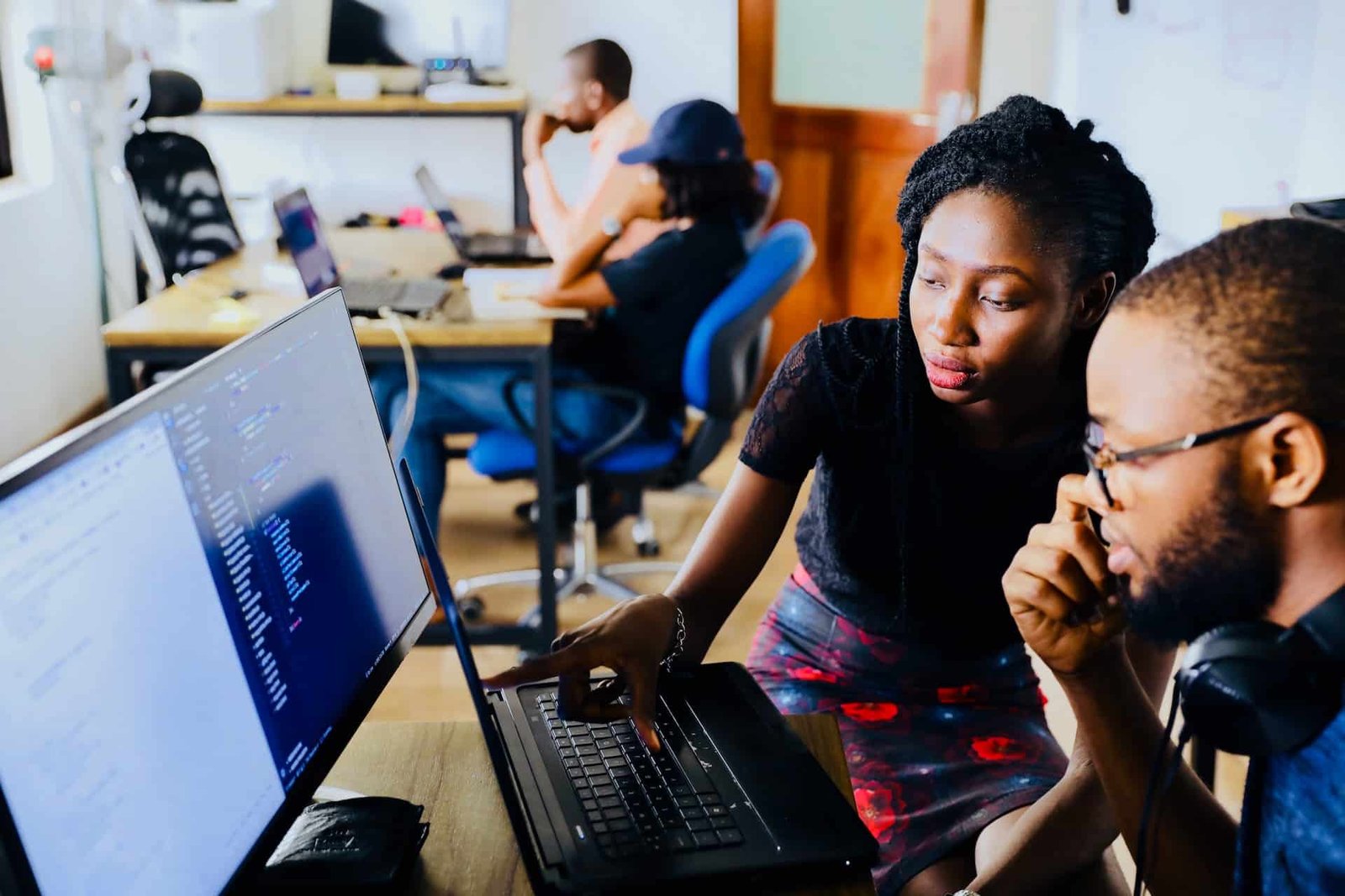 Two black web developers looking at code on a computer screen